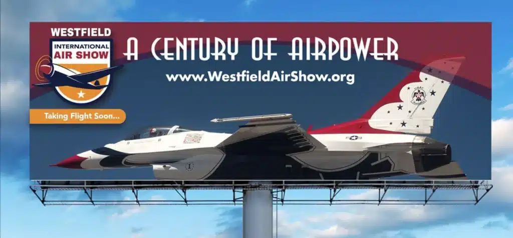 A billboard for the Westfield International Air Show features a fighter jet, the text A Century of Airpower, and the website www.WestfieldAirShow.org against a blue sky background.