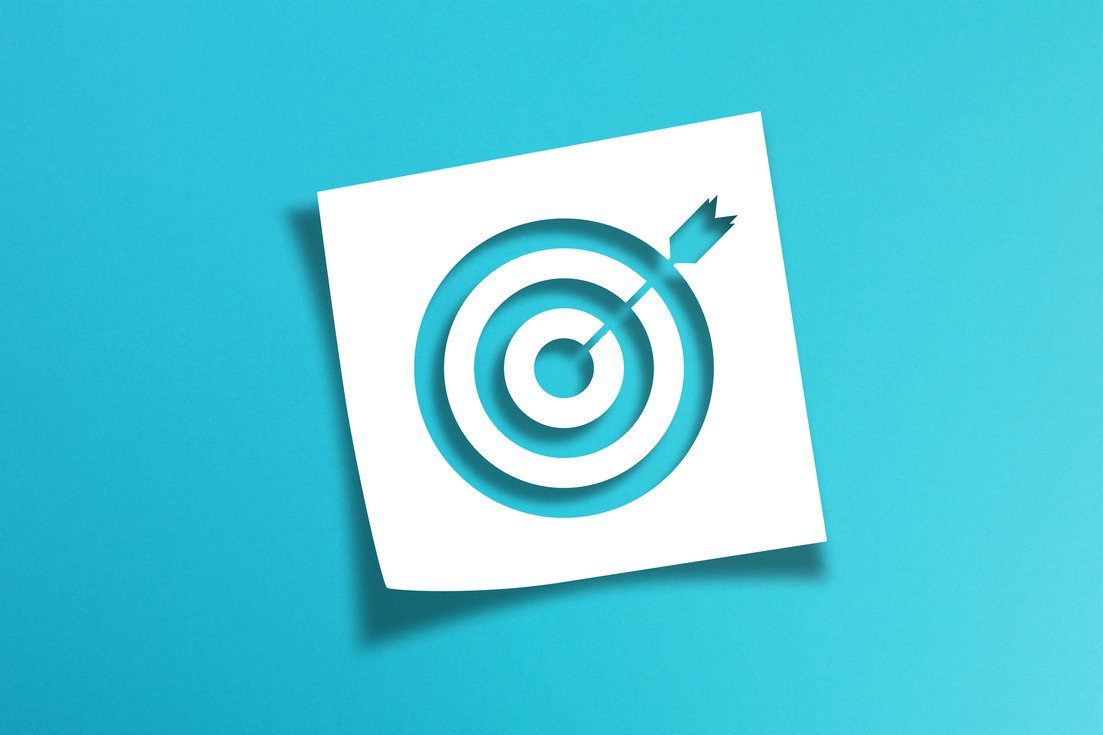 A white square with a cut-out design of a target and an arrow hitting the bullseye, placed on a bright blue background.