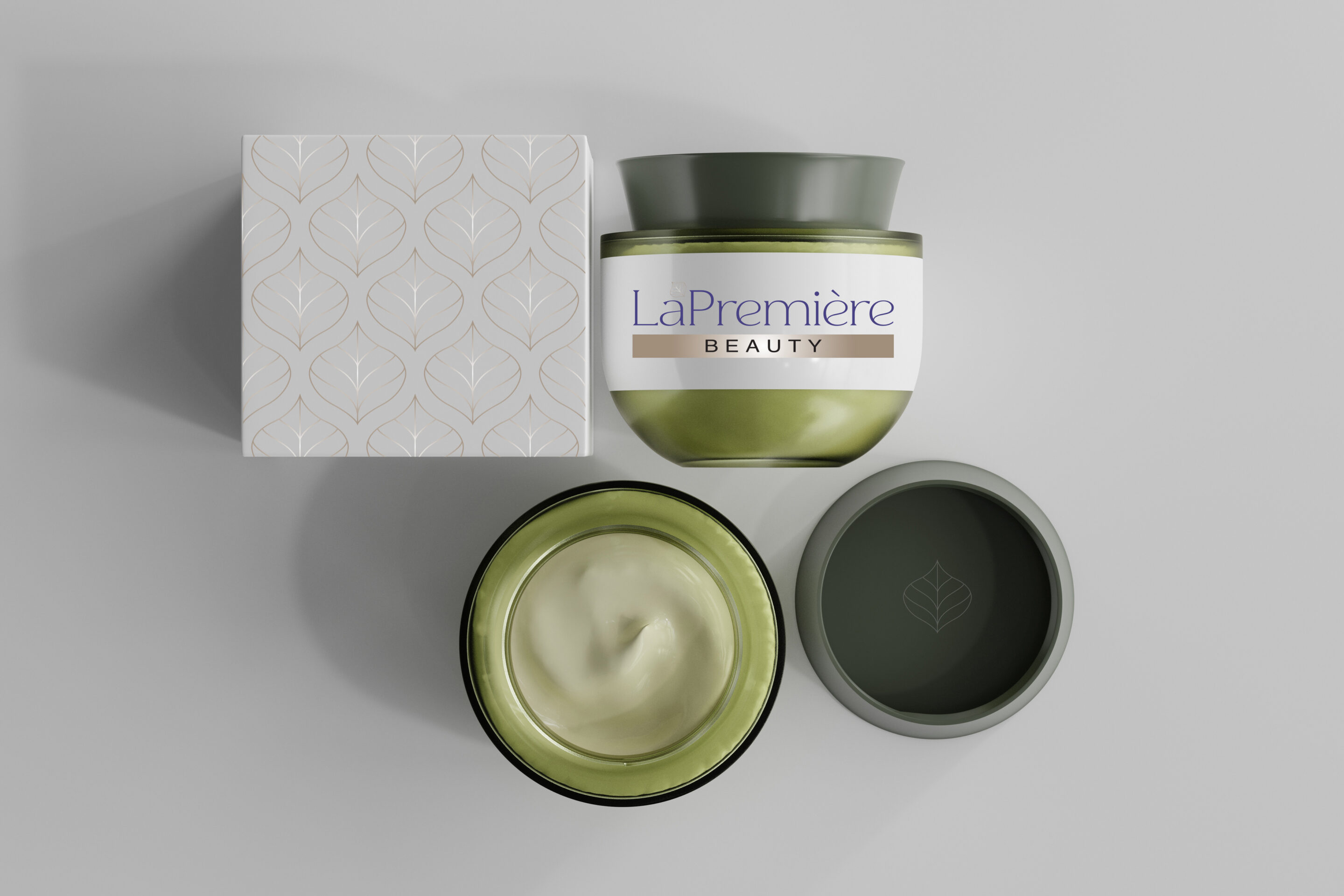 A green jar of LaPremière Beauty cream with its lid off, showing light green cream inside, sits next to a decorative box featuring a leaf pattern, all on a light gray surface.